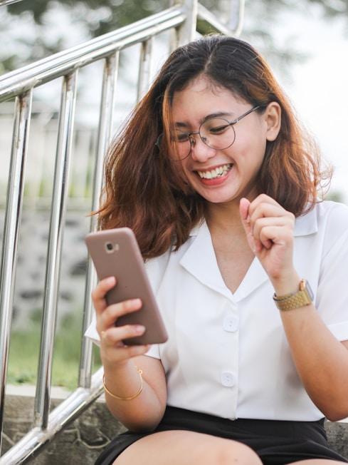 Persona sonriendo al usar su teléfono para gestionar finanzas